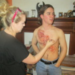 Mariah Johnson of Bioduck FX paints a burn wound onto Sam Lukowski's chest.